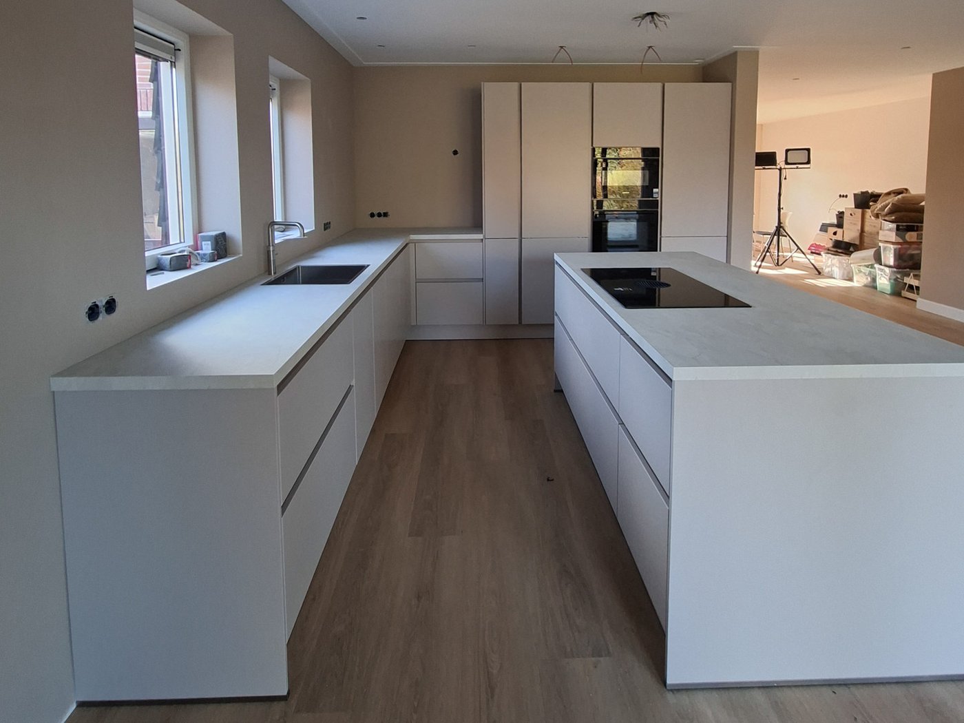 Moderne keuken met een wit eiland, houten krukken en zwarte hanglampen