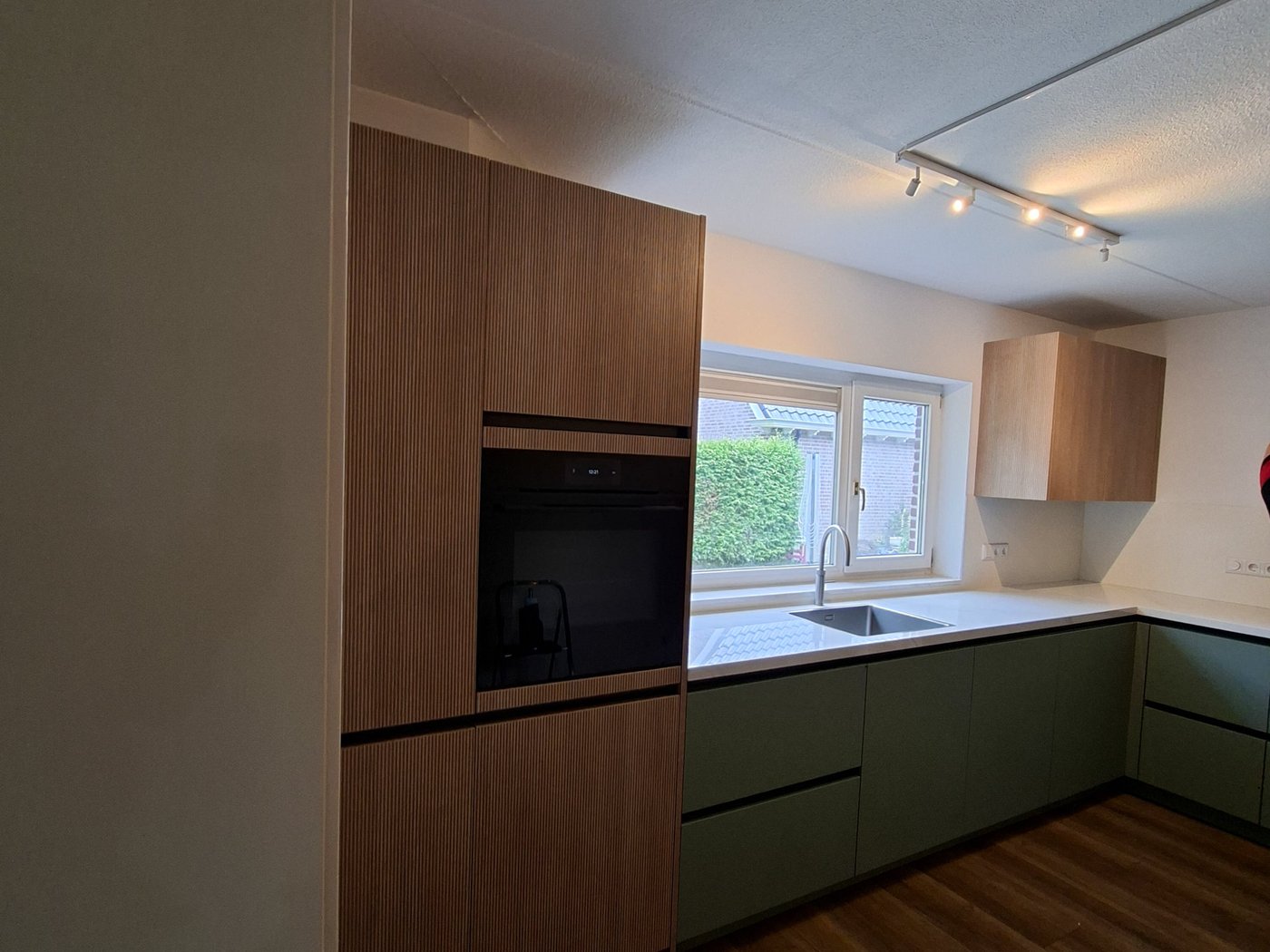 Witte keuken met donkere achterwand, eiland en zwarte hanglampen