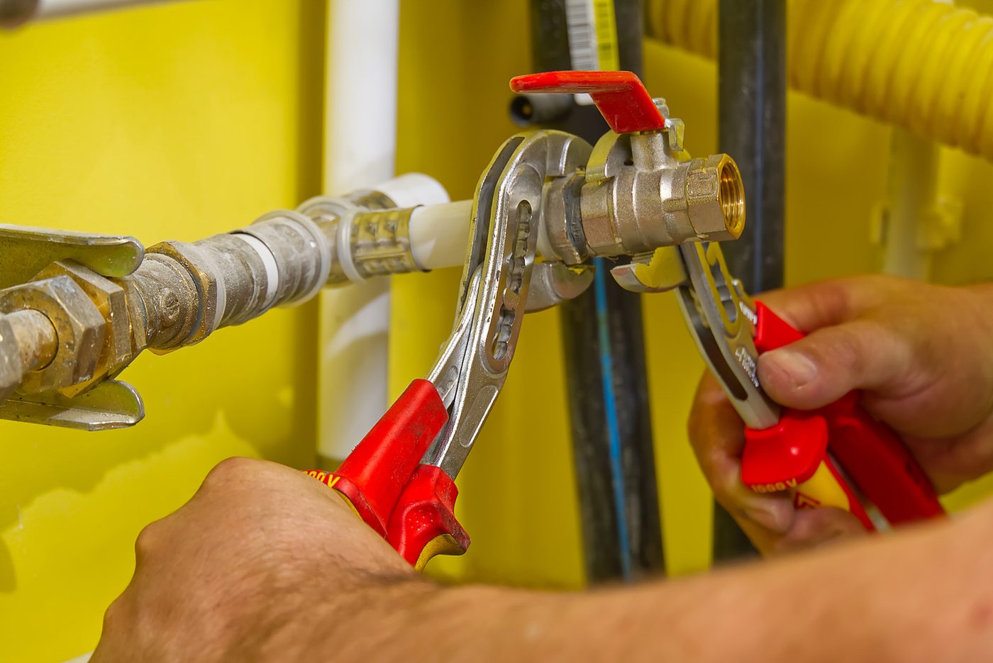 Handen die met waterpomptangen een afsluiter aandraaien